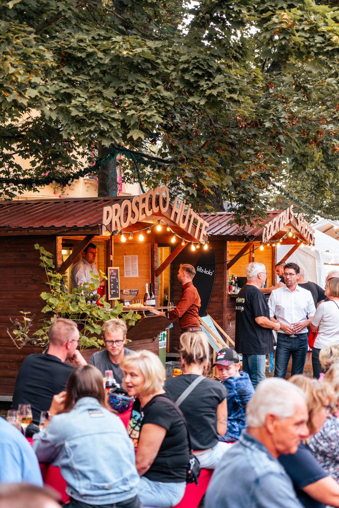 Gäste treffen sich an der Prosecco-Hütte und genießen Getränke beim Weinfest